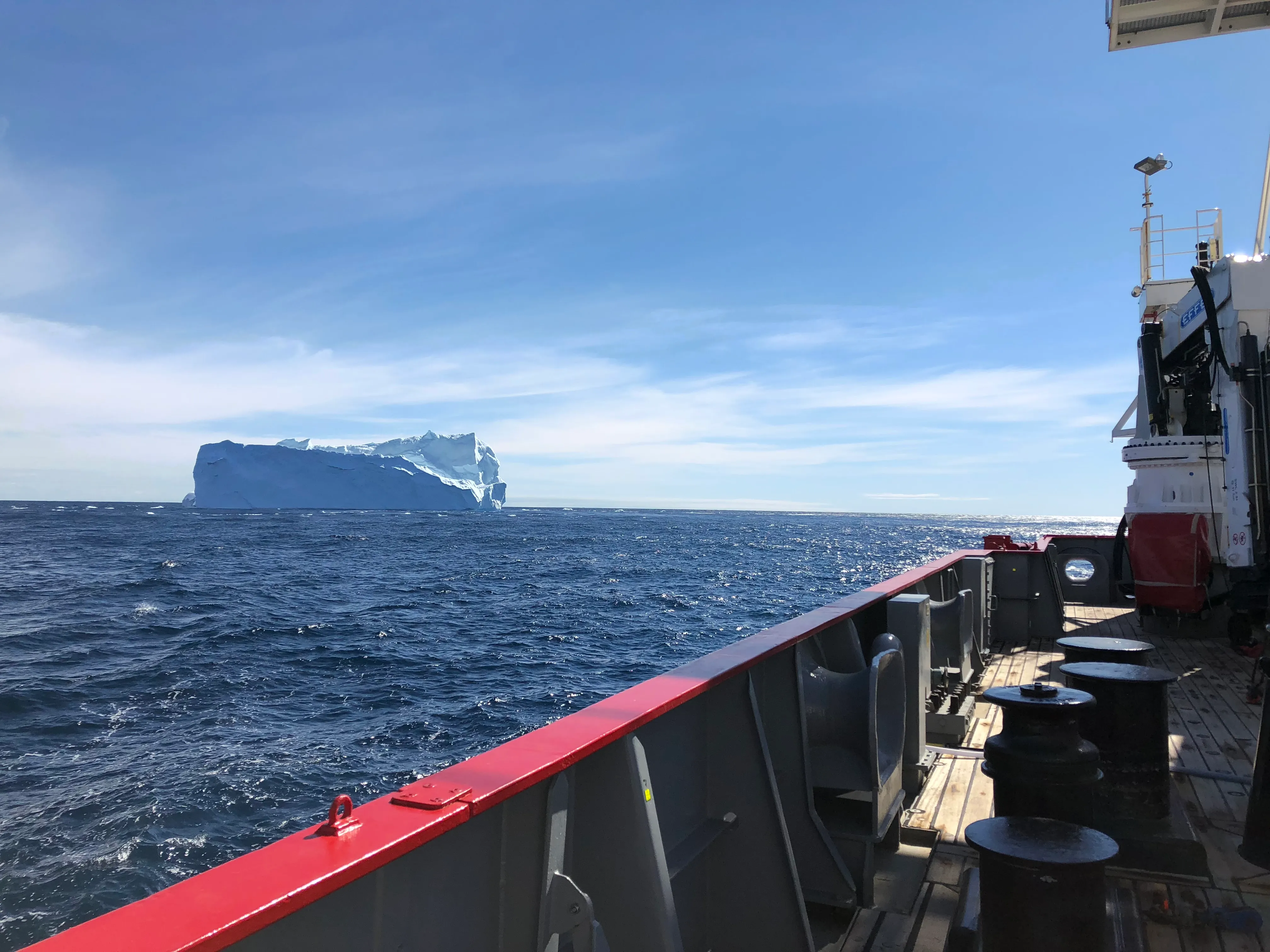 View from a research vessel toward an iceberg on the open ocean